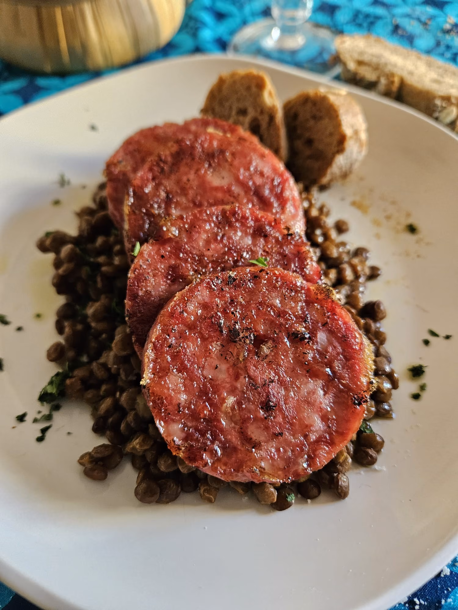 Sliced cotechino on braised lentils with crusty bread