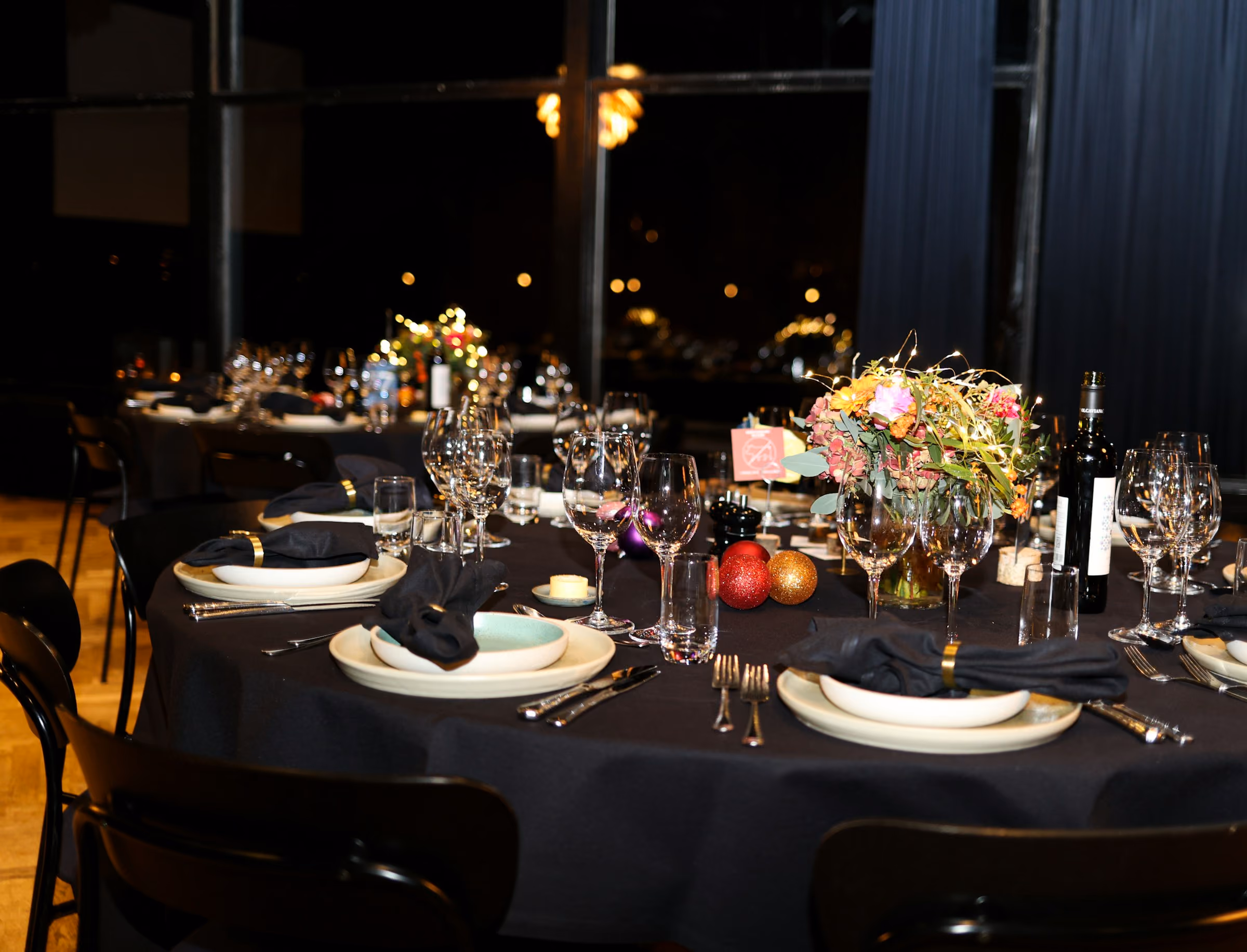 Round gala tables dressed in black with flowers