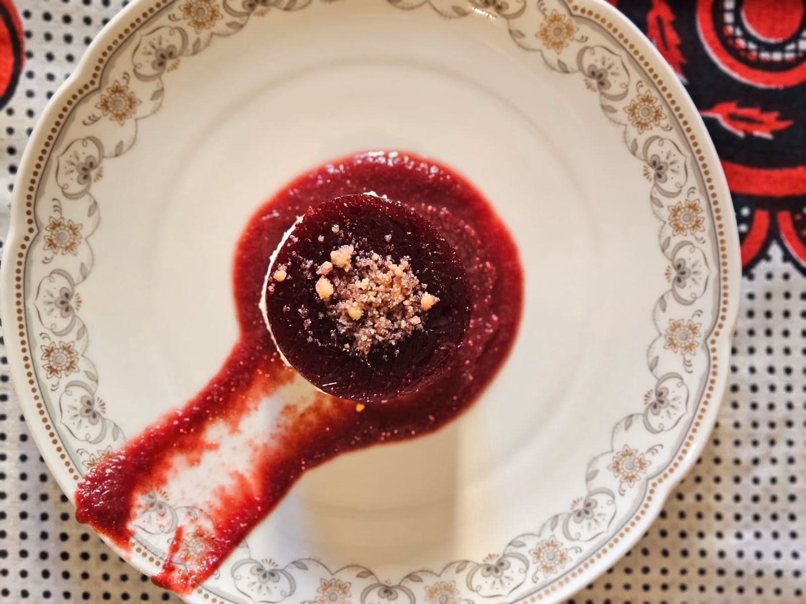 Panna cotta with berry coulis swept across a vintage plate, seen from above