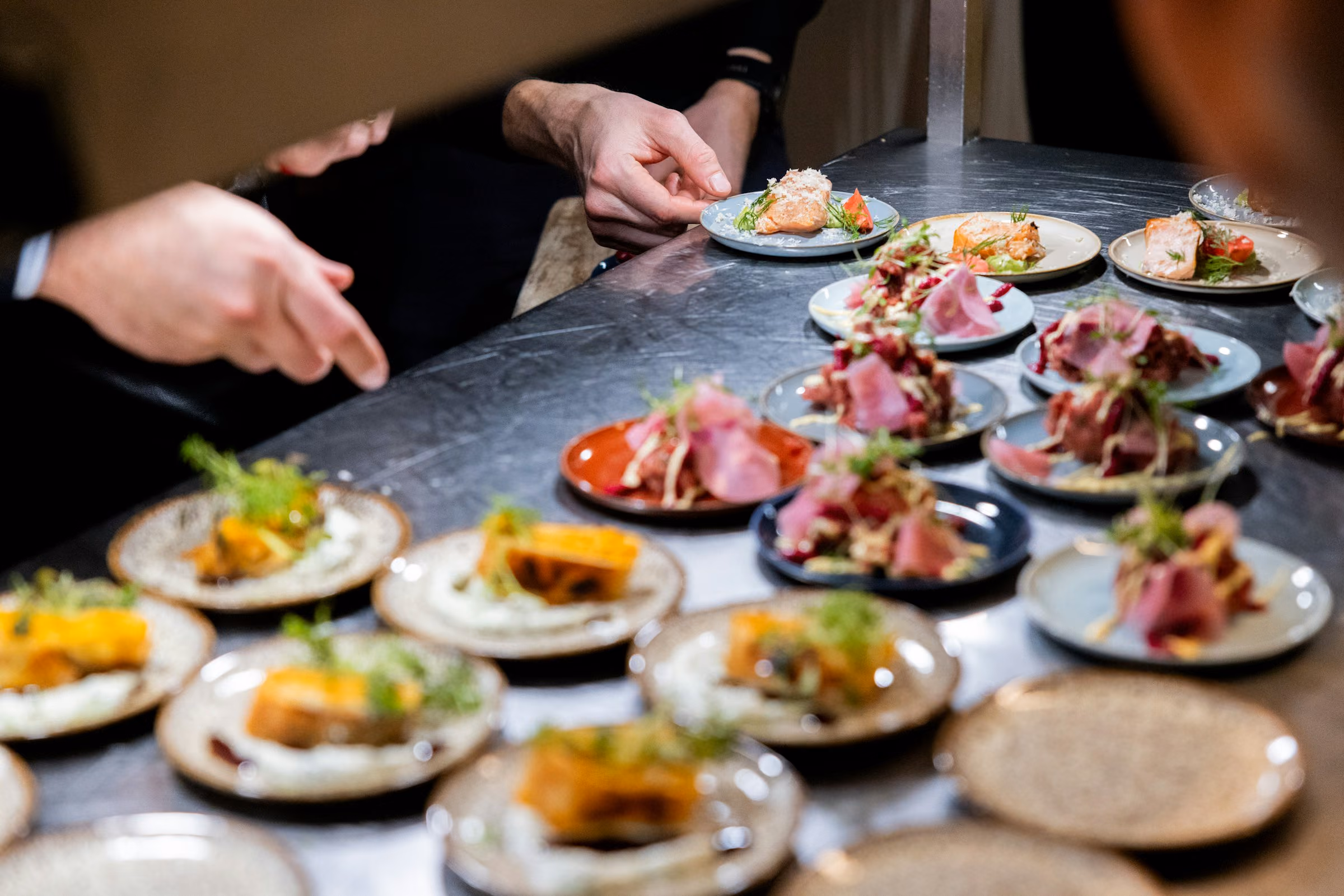Rows of plates being finished at the pass for a seated dinner