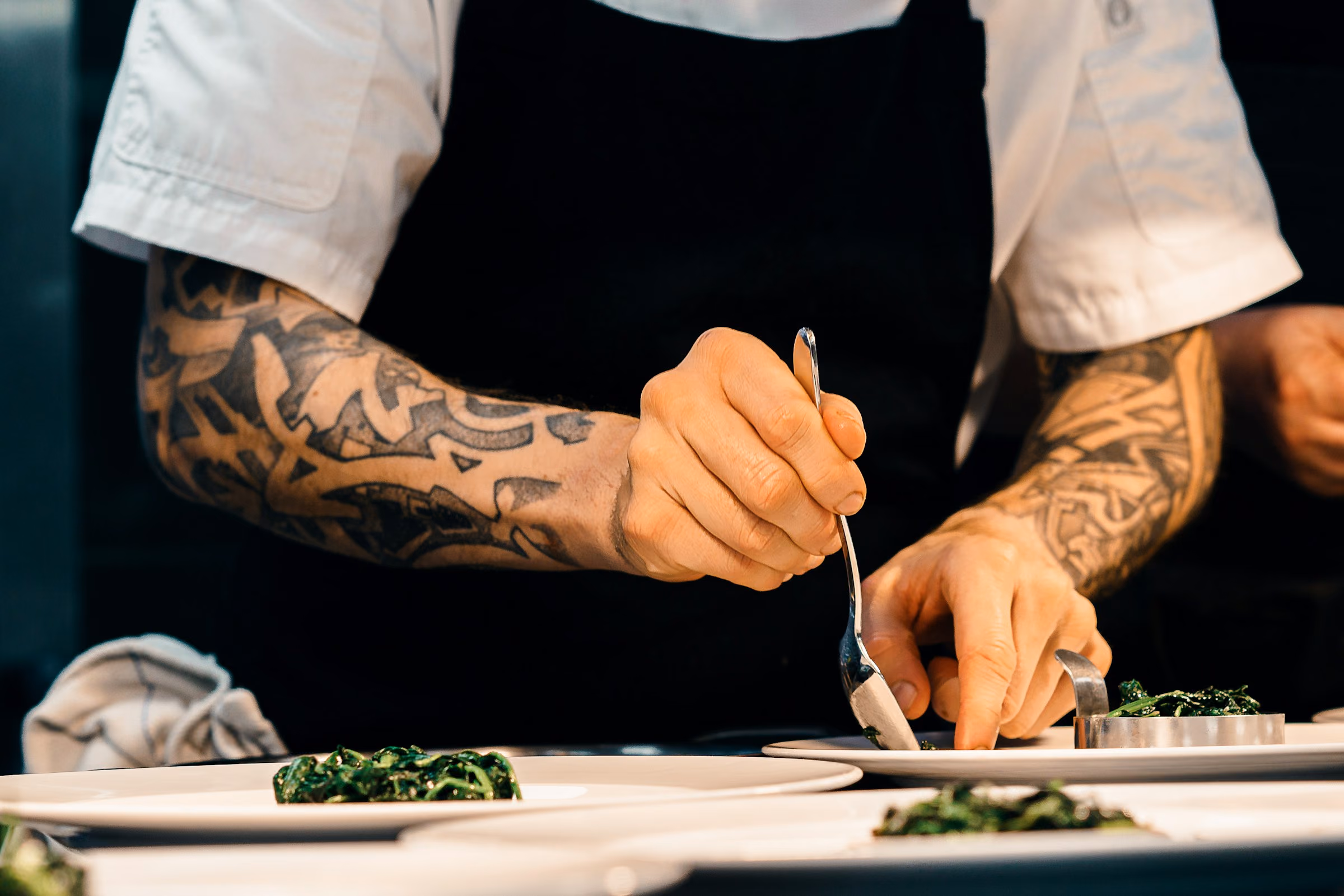 Chef’s hands placing a garnish with tweezers