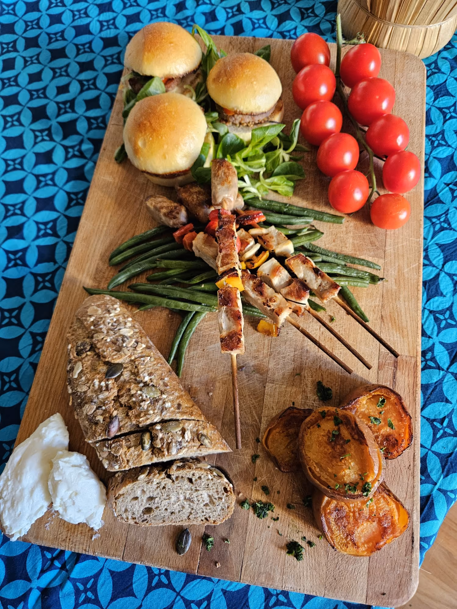 Sharing board with brioche sliders, grilled chicken skewers, seeded bread and vine tomatoes